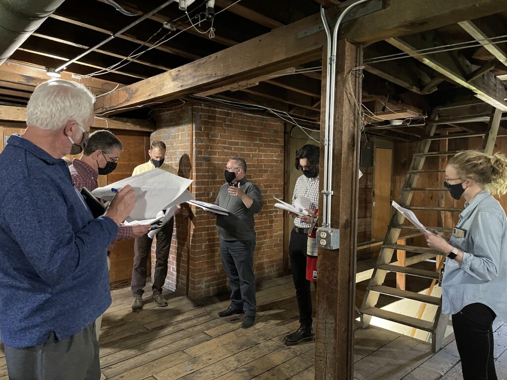 Staff and Contractors reviewing plans in the attic